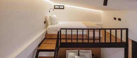 A compact hotel room with a bunk bed, a small desk, and a bedside table.