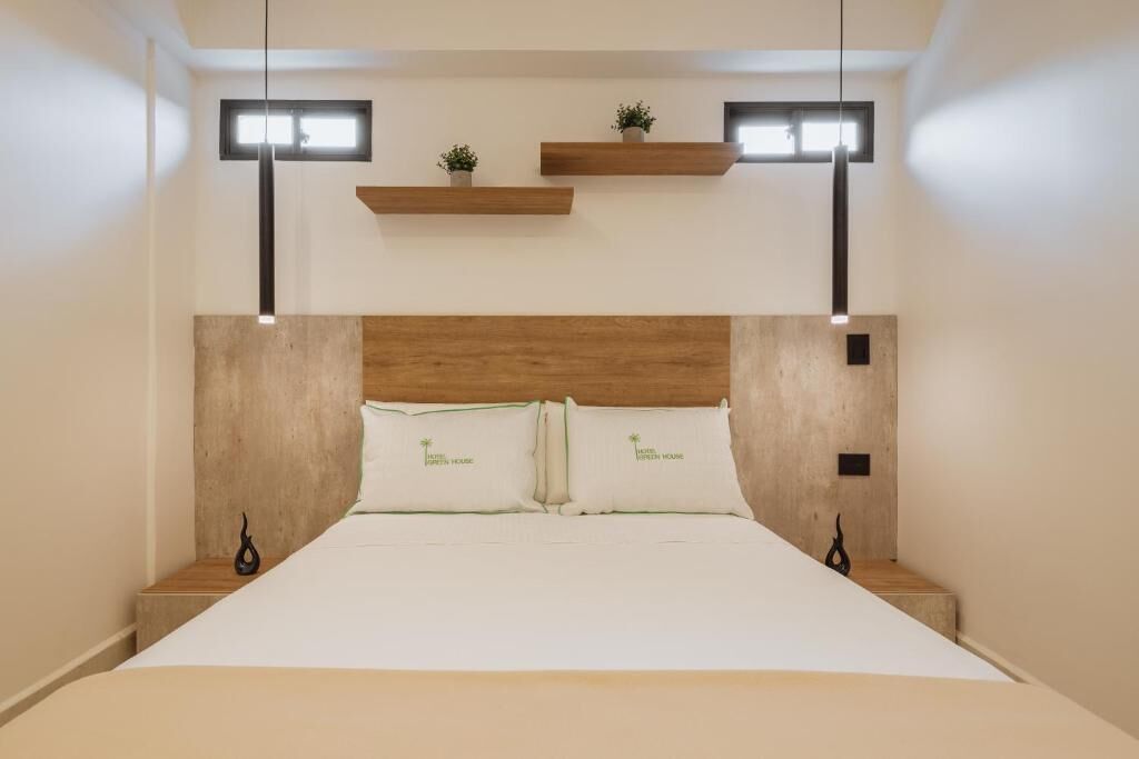 A bedroom with a wooden headboard, a bed with white bedding, two bedside tables, and two wall-mounted lights.