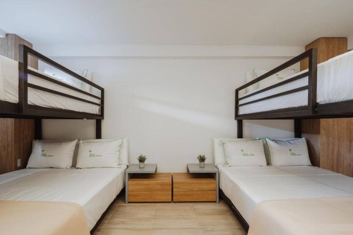 A room with two bunk beds, each with a small bedside table and a plant.