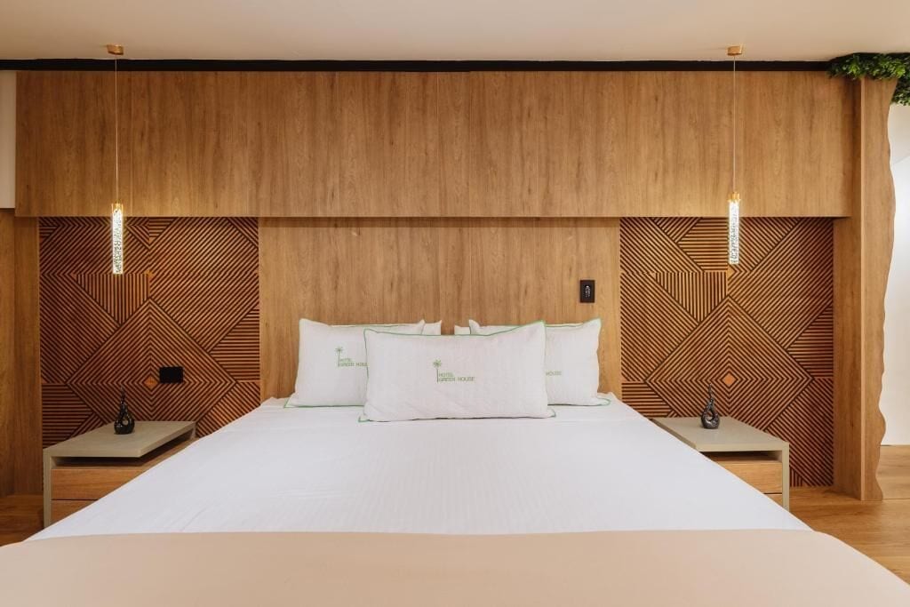 A hotel room with a large bed, two bedside tables, and a wooden headboard with geometric patterns.