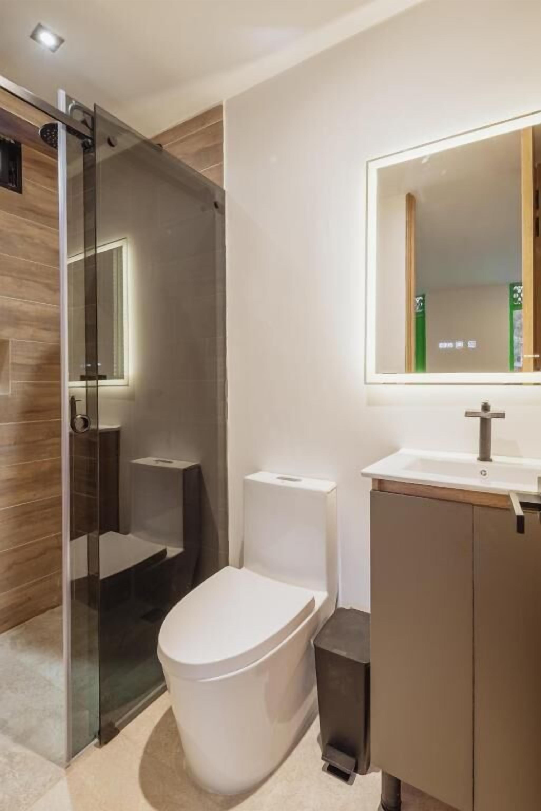 Un bagno moderno con doccia vetrata, un water bianco e un mobile lavabo con specchio.