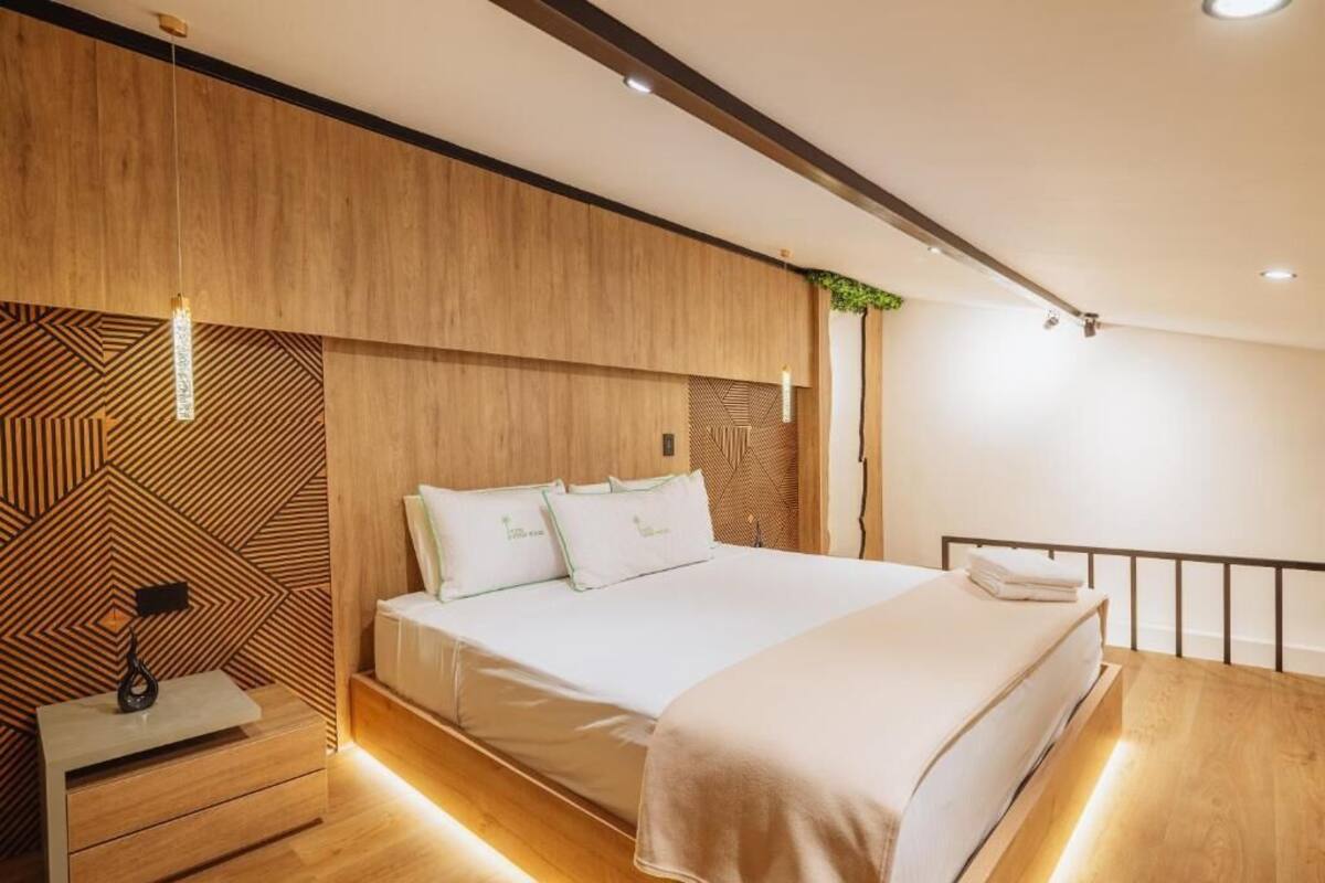 A modern bedroom with a wooden headboard, a bedside table, and a bed with white bedding.