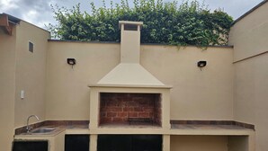 Een buitenkeuken met een bakoven, een spoelbak en een kleine zithoek.