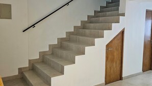 Een trap met een leuning, een houten deur en een betegelde vloer.