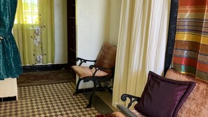 A room with a checkered floor, a sofa with a cushion, a chair, and a curtain. - Rooftop del quinto (Fès)