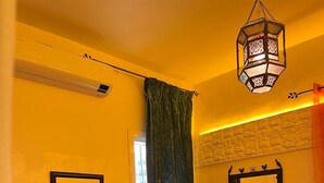 A room with a red sofa, a round coffee table, a checkered floor, and a hanging lantern. - Rooftop del quinto (Fès)