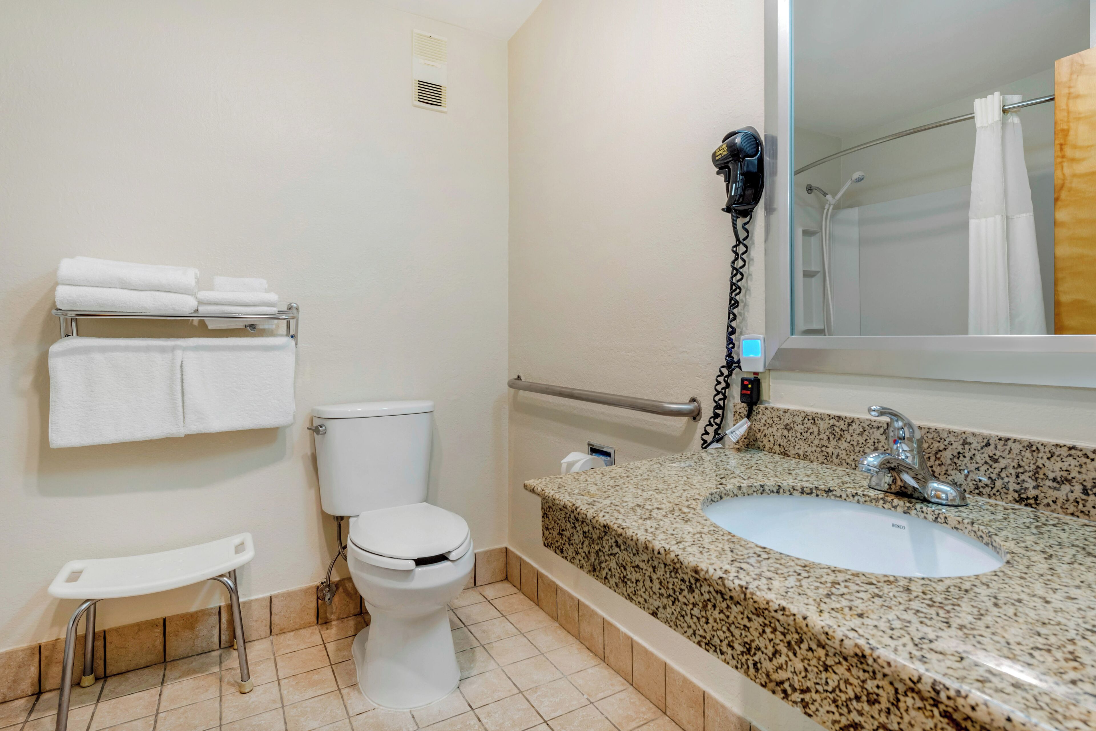 A bathroom with a toilet, a sink, a towel rack, and a shower area.