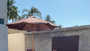 Ein Sitzbereich im Freien mit Tisch und Stühlen, ein weißer Liegestuhl und eine Wand mit einem Schild.