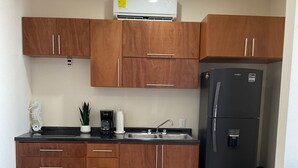 Eine moderne Küche mit Holzschränken, einem schwarzen Kühlschrank und einer Klimaanlage.