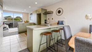 Een moderne keuken met een centraal eiland, barstoelen en een eethoek met een tafel en stoelen.