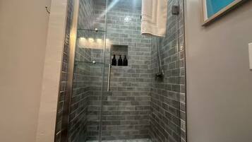 Une douche avec des portes en verre, des murs carrelés et une serviette accrochée au mur.
