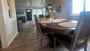 A dining area with a round table, chairs, and a vase of flowers. - Monterey Bay Escape (Seaside)