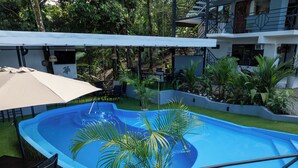 A swimming pool with a surrounding patio area, including a table and chairs, and a covered seating area. - Hotel Manuel antonio beracha (Quepos)
