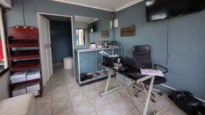 A small office with a desk, chair, and shelves. There is a mirror, a television, and a trash can. - Hotel Manuel antonio beracha (Quepos)