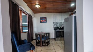 A compact kitchen with a refrigerator, stove, and a dining area with a table and chairs. - Hotel Manuel antonio beracha (Quepos)