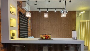 Une cuisine moderne dotée d’un îlot central, de tabourets de bar, de luminaires suspendus et d’un panier à fruits.