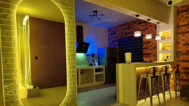 Une cuisine moderne dotée d’un îlot central, de tabourets de bar et d’un mur d’accent en briques.