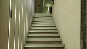 Un escalier avec une main courante à gauche et un mur à droite.