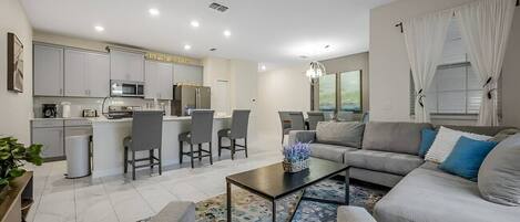 A modern living room with a sofa, coffee table, and a dining area with chairs.