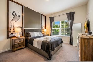 A bedroom with a bed, bedside tables, a TV, and a window with curtains. - Luxury 4BR Villa w Pool Near Disney Parks (Davenport)