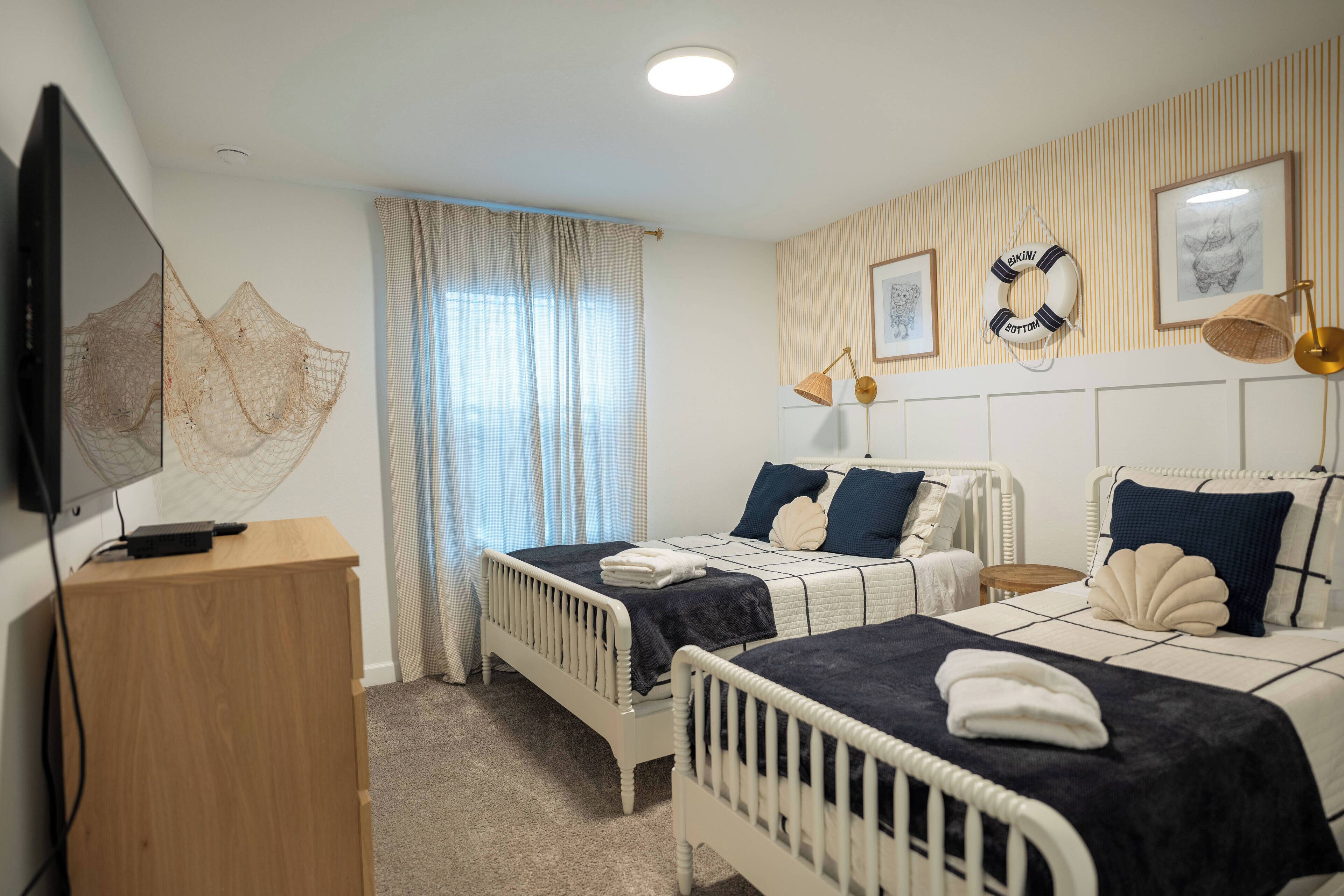 A bedroom with two beds, a TV, and a wooden dresser.