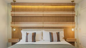 A modern bedroom with a wooden headboard, bedside lamps, and a neatly made bed. - Luxury Home With Pool Game Room Cinema (Kissimmee)