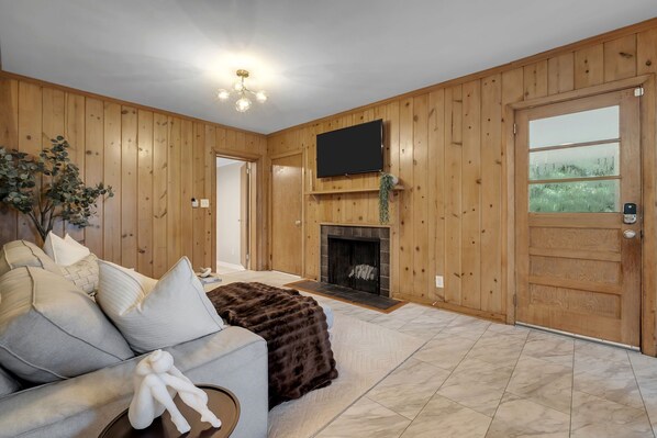 A living room with a sofa, a fireplace, and a television mounted on the wall.