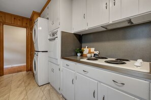 A compact kitchen with white cabinets, a built-in stove, and a washing machine. - Parkside at San Luis • 8 Beds • 5 Bedrooms • 2 Bathrooms in Hallway (Tallahassee)