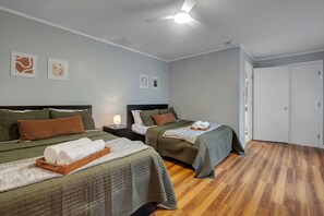 A hotel room with two beds, a ceiling fan, and a door.