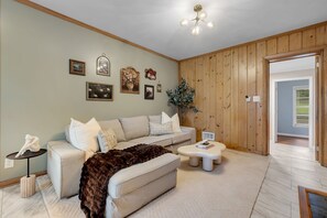 A living room with a sofa, a coffee table, and a decorative plant. - Parkside at San Luis • 8 Beds • 5 Bedrooms • 2 Bathrooms in Hallway (Tallahassee)