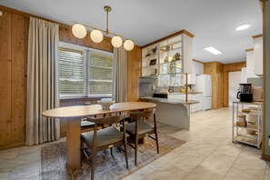 A modern kitchen with wooden cabinets, a central island, and a dining area with a round table and chairs. - Parkside at San Luis • 8 Beds • 5 Bedrooms • 2 Bathrooms in Hallway (Tallahassee)