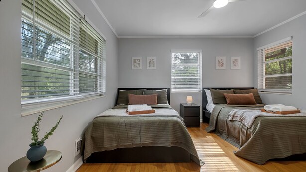 Un dormitorio con dos camas, un ventilador de techo y una mesita de noche con lámpara.
