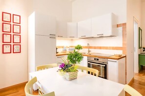 A compact kitchen with white cabinets, a wooden countertop, and a dining table with chairs. - Caralis Home is an elegant apartment just steps from Cagliari's historic sites.Ideal for families who want to enjoy a comfortable holiday in Cagliari's historic center, discovering its most fascinating secrets and traditions.Caralis Home is fully air-con (Cagliari)