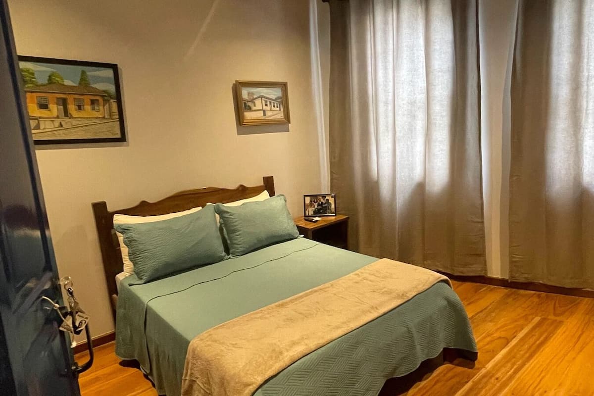 A bedroom with a bed, a nightstand, and two framed pictures on the wall.