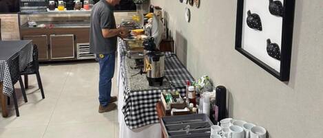 A kitchen area with a person preparing food, a coffee machine, and various kitchen utensils.