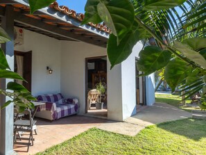 A covered outdoor seating area with a checkered sofa, a potted plant, and a tiled floor. - HOSTEL QUINTAL GUEST - Guarujá (Guarujá)