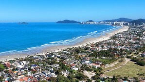 A coastal cityscape with a beach, residential areas, and high-rise buildings. - HOSTEL QUINTAL GUEST - Guarujá (Guarujá)