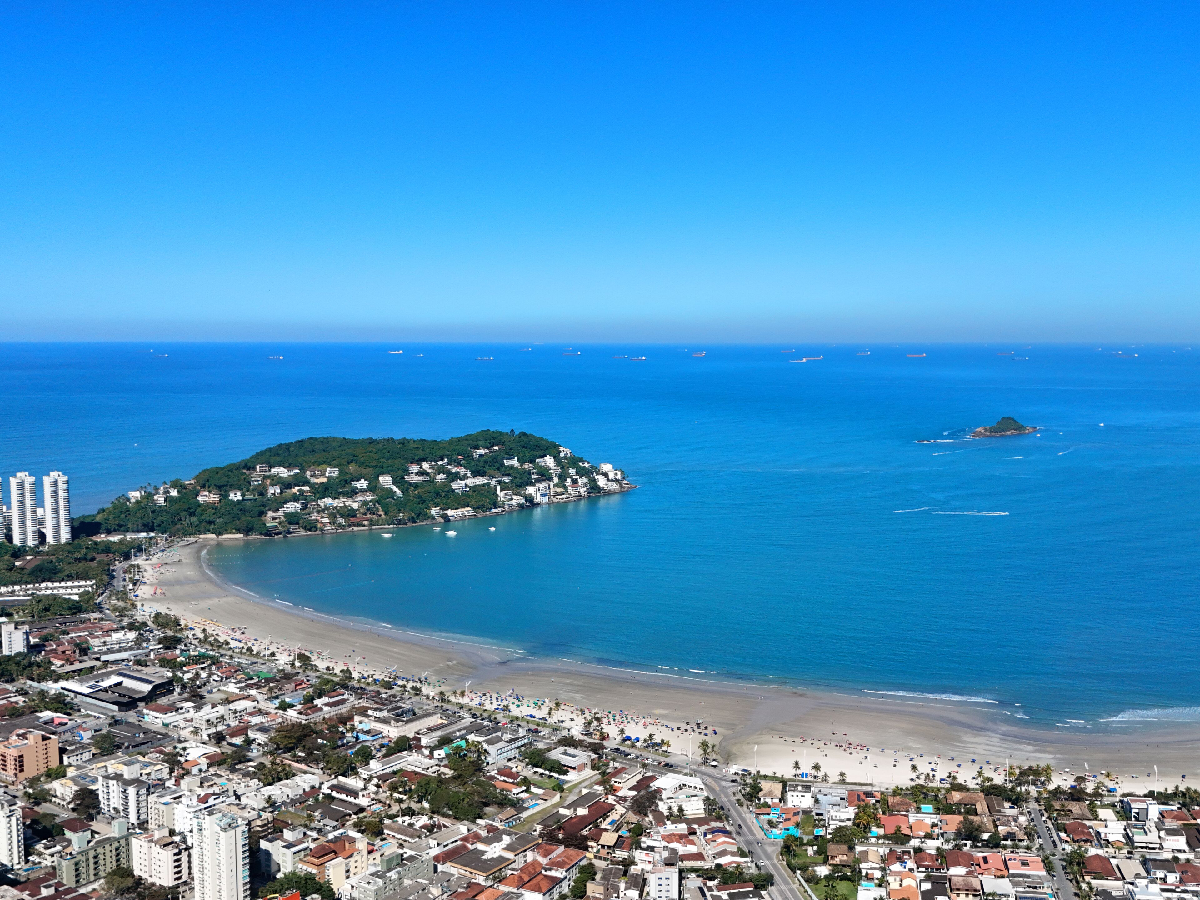Eine Küstenstadtlandschaft mit Strand, einer kleinen Insel und blauem Himmel.