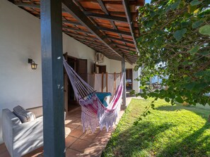 Un espacio al aire libre cubierto con una hamaca, un sofá y un patio con piso de baldosas.