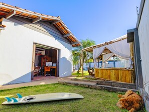 Ein Haus mit überdachter Terrasse, einem Surfbrett und einem Hund.