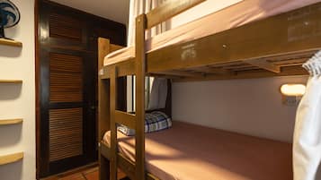 Une chambre avec un lit superposé, une échelle en bois, une table de chevet et une lampe fixée au mur.