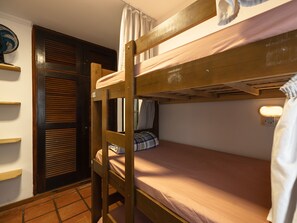 Ein Schlafraum mit Etagenbett, Holzleiter, Nachttisch und Wandleuchte.