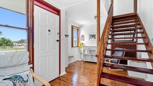 Une pièce avec un escalier en bois, une porte blanche et une vue sur l’extérieur.