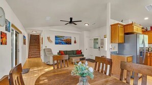 A spacious living area with a wooden dining table, a sofa, and a kitchen with wooden cabinets and a refrigerator. - Yosemite Terrace View Retreat (Mariposa)