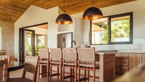 Une cuisine moderne avec des meubles en bois, un réfrigérateur en acier inoxydable et un coin repas doté de chaises en osier.