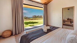 Une chambre avec une grande fenêtre, un lit, un miroir et un plafond en bois.