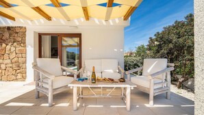 An outdoor seating area with white chairs and a table, a bottle of wine, and a book. - Nice home in San Teodoro (San Teodoro)