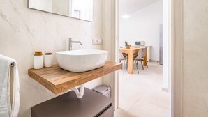 A modern bathroom with a large white vessel sink, wooden countertop, and a mirror above it. - Nice home in San Teodoro (San Teodoro)