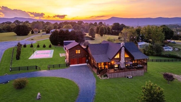 A large wooden lodge with a tennis court, surrounded by a lush landscape and mountains in the background. - Grand Mountain Lodge, Pickleball, Barrel Sauna, Hot Tub, Game Room, Arcade (Luray)