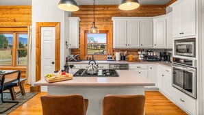 A modern kitchen with white cabinets, a central island, stainless steel appliances, and a view through a window. - Grand Mountain Lodge, Pickleball, Barrel Sauna, Hot Tub, Game Room, Arcade (Luray)
